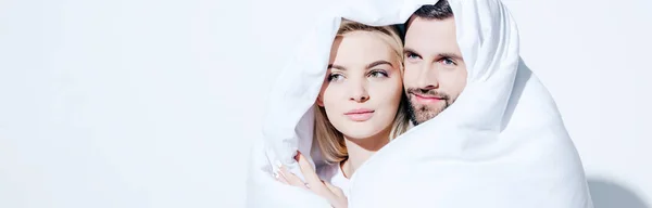 Panoramic shot of girlfriend and boyfriend covered in blanket looking away on white — Stock Photo
