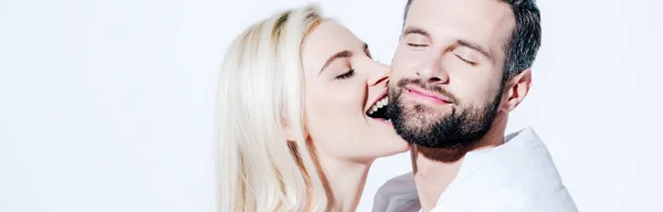 Panoramic shot of girlfriend biting cheek of boyfriend covered in blanket on white — Stock Photo