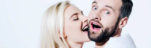 Panoramic shot of girlfriend biting cheek of boyfriend covered in blanket on white — Stock Photo