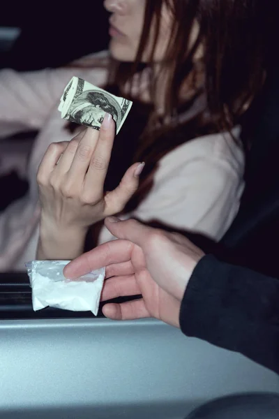 Vista recortada de la mujer en coche con billetes de dólar la compra de drogas de matón - foto de stock