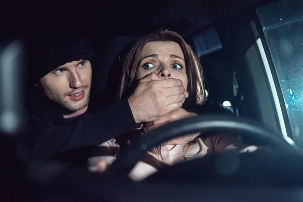 Ladrón estrangulando hermosa mujer asustada en coche - foto de stock