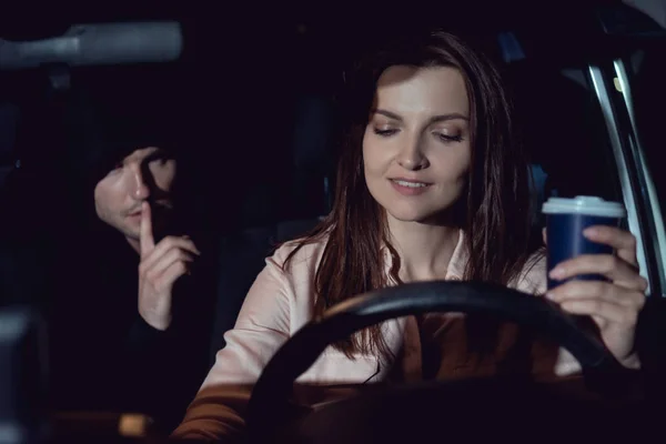 Ladro fare silenzioso gesto vicino bella sorridente donna in auto — Foto stock