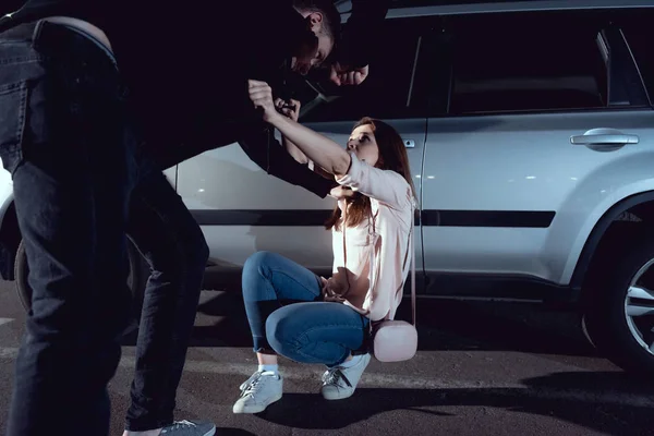 Thief attacking scared woman near car at night — Stock Photo