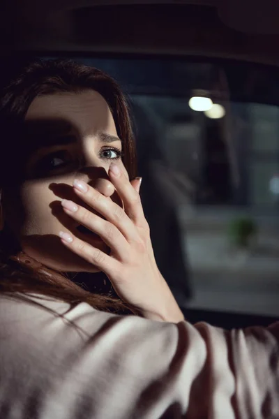 Испуганная женщина смотрит в камеру и прикрывает рот в машине — стоковое фото