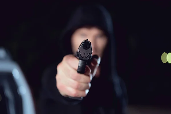 Selective focus of gun in hand of thief in black hoodie — Stock Photo