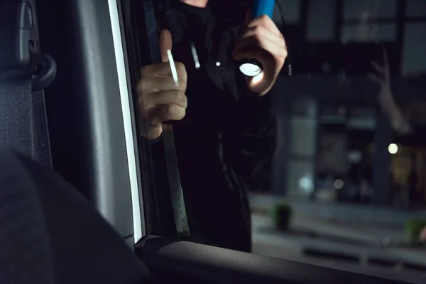 Dieb dringt mit Taschenlampe und Brecheisen in Auto ein — Stockfoto
