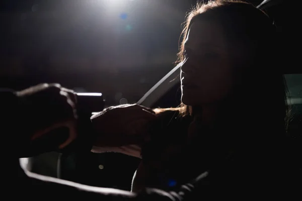 Злодій вказує пістолет на жінку, сидячи в машині вночі з заднім світлом — стокове фото