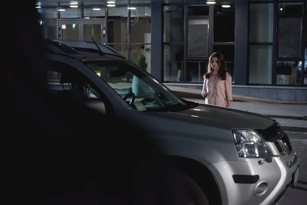 Femme effrayée près de la voiture dans le parking la nuit — Photo de stock