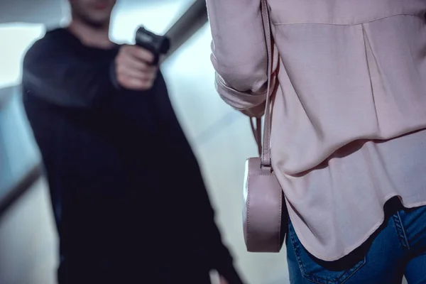 Cropped view of robber pointing gun at woman — Stock Photo