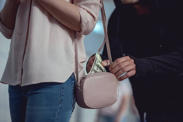 Cropped view of thief stealing dollar banknotes from bag of woman — Stock Photo