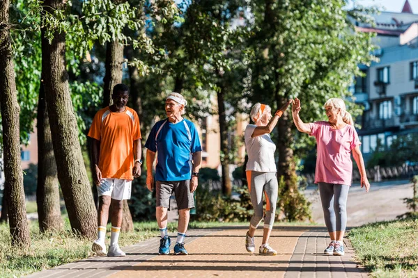 Glückliche Seniorinnen geben High Five im Park bei multikulturellen Rentnern — Stockfoto