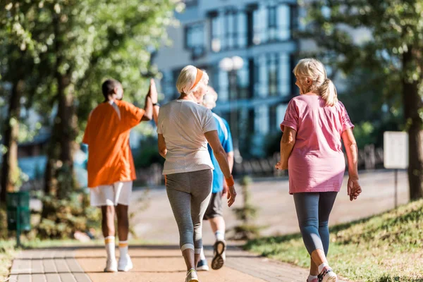 Selective focus of senior women running near multicultural retired men — Stock Photo