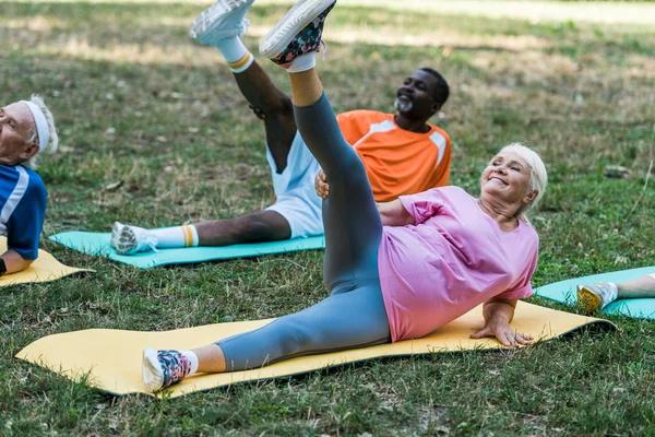 Sénior afroamericano hombre y mujer haciendo ejercicio en fintess esteras - foto de stock