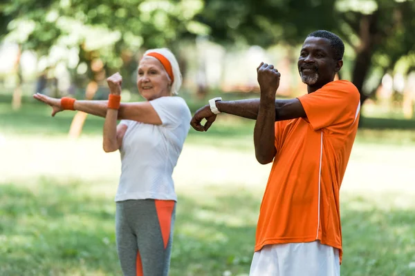 Selective focus of happy senior african american man working out with retired woman — Stock Photo