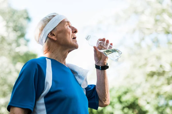 Vue à angle bas de l'homme âgé tenant la bouteille avec de l'eau — Photo de stock