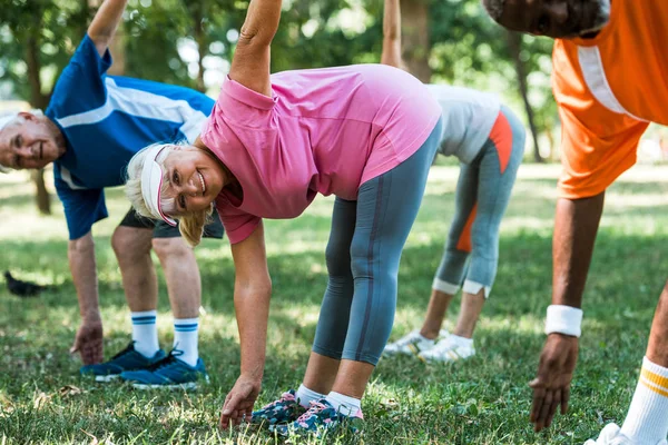 Vista recortada de los pensionistas multiculturales haciendo ejercicio en el parque - foto de stock