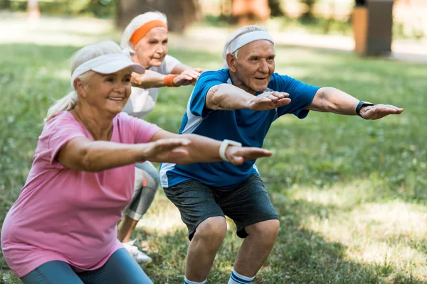 Selective focus of retired man doing sit ups with senior women — Stock Photo