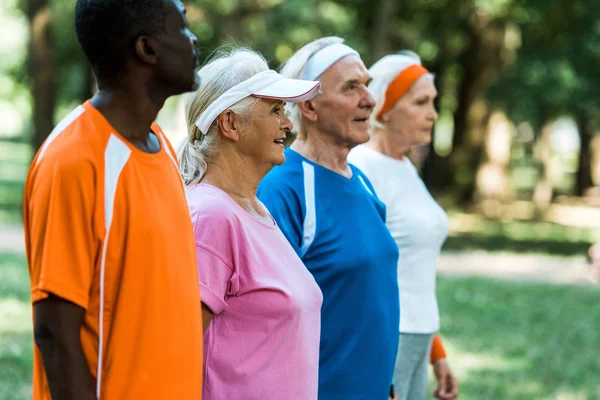 Selective focus of senior woman in cap near retired multicultural pensioners — Stock Photo