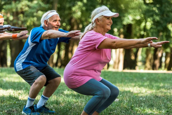 Fröhliche multikulturelle Rentner beim Sit-ups auf dem Gras — Stockfoto