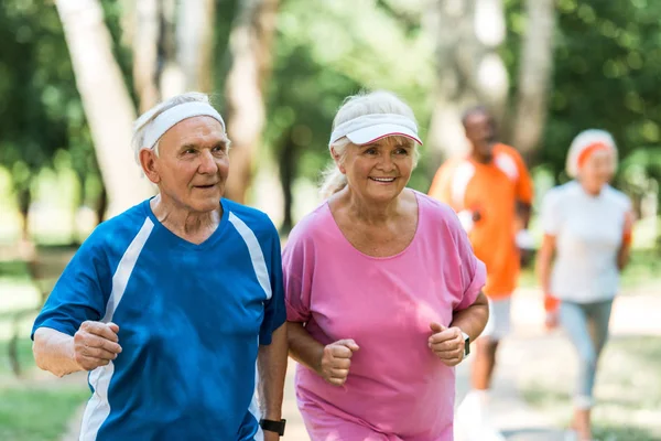 Enfoque selectivo de la pareja jubilada feliz ejercicio al aire libre - foto de stock