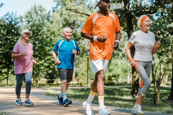 Sportliche multikulturelle und pensionierte Männer und Frauen, die im Park laufen — Stockfoto