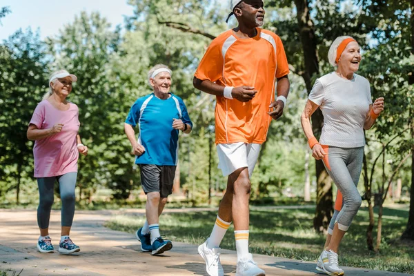 Hombres y mujeres deportivos multiculturales y jubilados corriendo en el parque - foto de stock