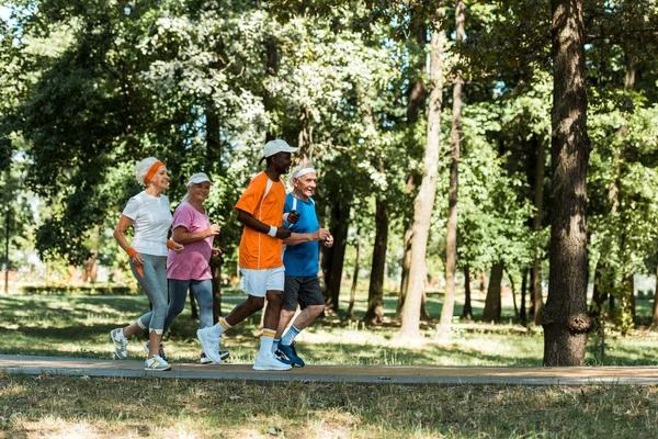 Homens e mulheres multiculturais e seniores alegres que correm no parque — Fotografia de Stock