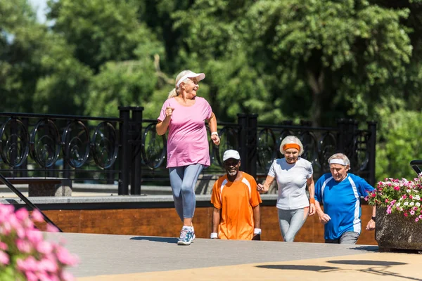 Concentrazione selettiva della donna in pensione felice che corre vicino a pensionati multiculturali anziani — Foto stock