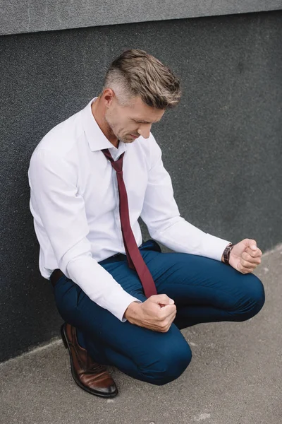 Upset businessman sitting with clenched fists outside — Stock Photo