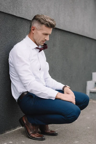 Verärgerter Geschäftsmann in offizieller Kleidung sitzt draußen — Stockfoto