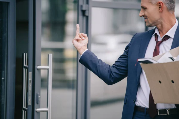 Handsome man in suit showing middle finger while looking at door — Stock Photo