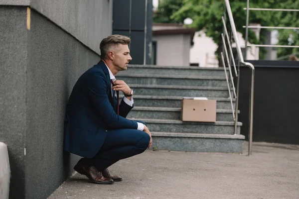 Side view of upset businessman touching tie outside — Stock Photo