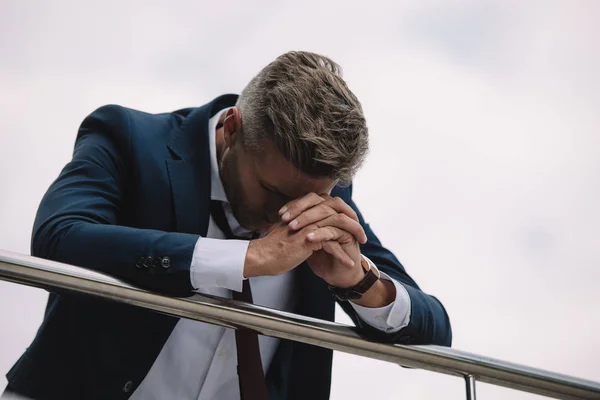 Molesto hombre de negocios en traje de pie afuera con las manos apretadas - foto de stock