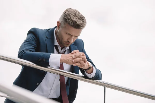 Selektiver Fokus eines aufgebrachten Geschäftsmannes im Anzug, der mit geballten Händen draußen steht — Stockfoto