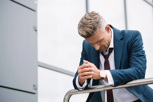 Hombre molesto en desgaste formal de pie cerca del edificio con las manos apretadas — Stock Photo