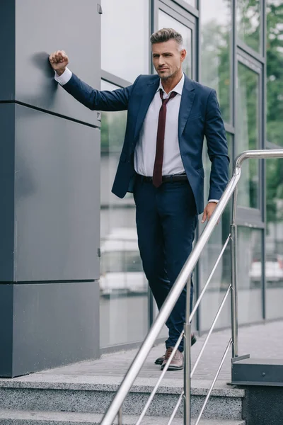 Вибірковий фокус незадоволеної людини в офіційному одязі, що стоїть біля будівлі — стокове фото