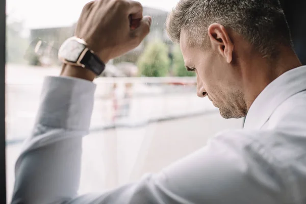 Selective focus of sad businessman standing with clenched fist near window — Stock Photo