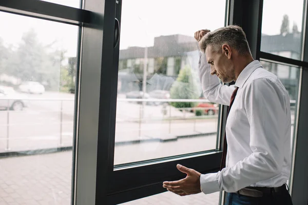 Bouleversé homme d'affaires debout avec le poing serré près des fenêtres — Photo de stock