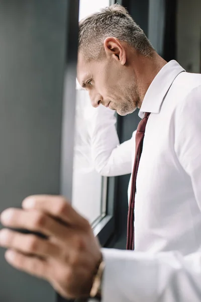 Enfoque selectivo de empresario molesto en traje cerca de la ventana — Stock Photo