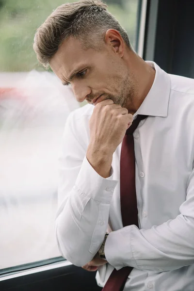 Molesto empresario tocando la cara mientras está de pie cerca de la ventana - foto de stock