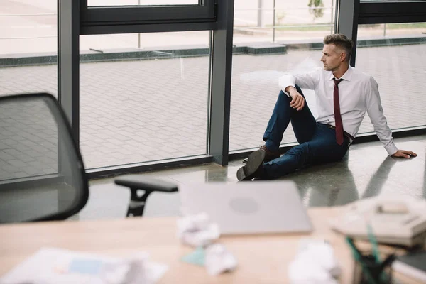 Вибірковий фокус людини, що сидить на підлозі біля робочого місця — стокове фото
