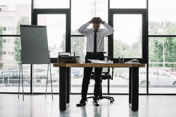 Uomo d'affari che tocca la testa mentre guarda il tavolo in ufficio — Foto stock