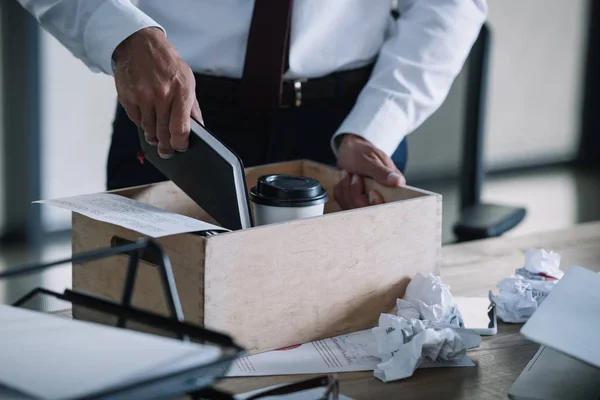 Abgeschnittene Ansicht eines Mannes, der Notizbuch in Holzkiste neben Pappbecher und zerknüllte Papierkugeln auf den Tisch legt — Stockfoto