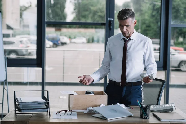 Homme d'affaires dans l'usure formelle geste près de la table de boîte dans le bureau — Photo de stock