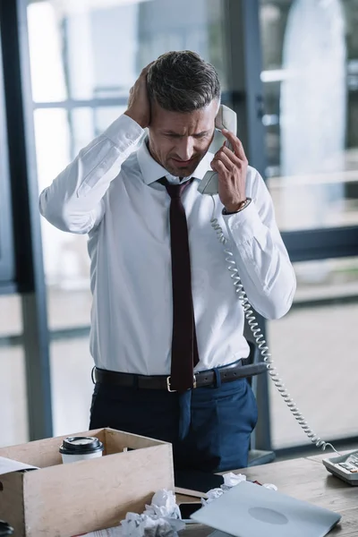 Chateado empresário falando no telefone retro perto da caixa na mesa — Fotografia de Stock
