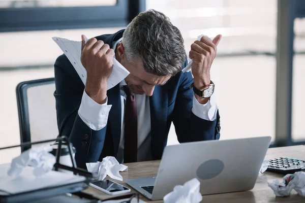 Enfoque selectivo del hombre frustrado en traje con papel arrugado cerca de la computadora portátil - foto de stock