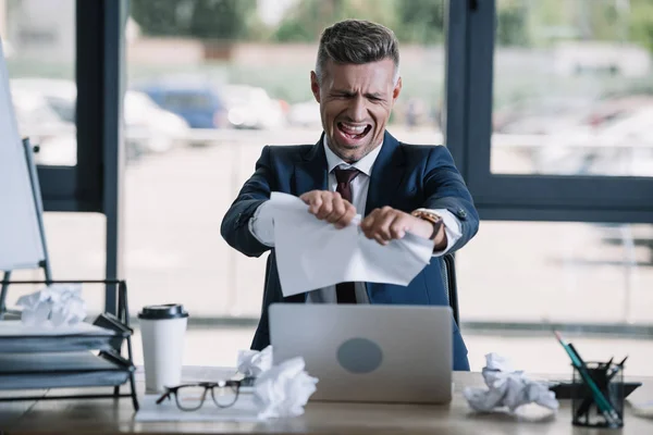 Foco seletivo do homem irritado gritando enquanto rasgando papel perto copo descartável — Fotografia de Stock