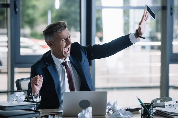 Angry businessman throwing in air smartphone with blank screen — Stock Photo