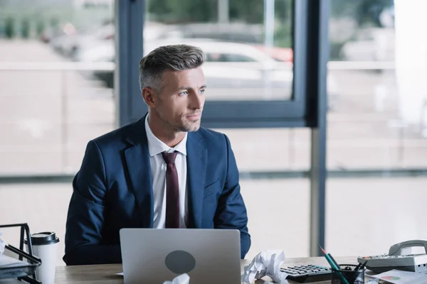 Hombre de negocios guapo en traje sentado en la oficina moderna - foto de stock