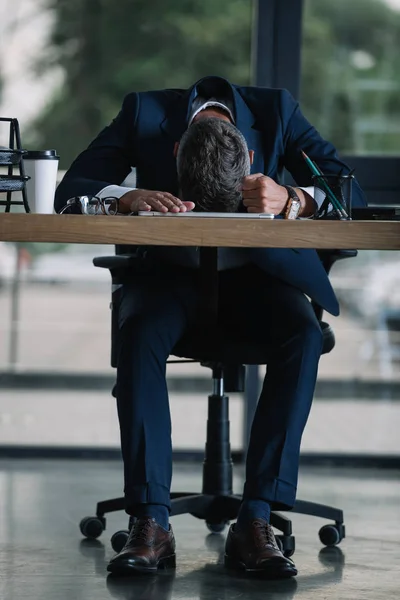Hombre sentado cerca de escritorio con taza de papel en la oficina moderna - foto de stock